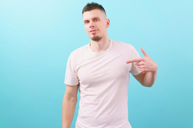 Man pointing his finger at a white blank t-shirt on a blue Template Young Casual Commercial