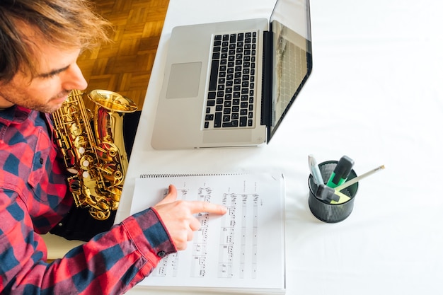 Photo man pointing over notes on sheet music during his saxophone online course