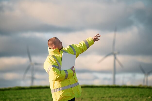 Man pointing at the sky while standing near wind turbines Sustainable future and renewable power sources concept