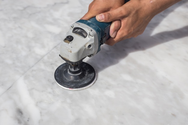 Man polishing marble stone table by small angle grinder