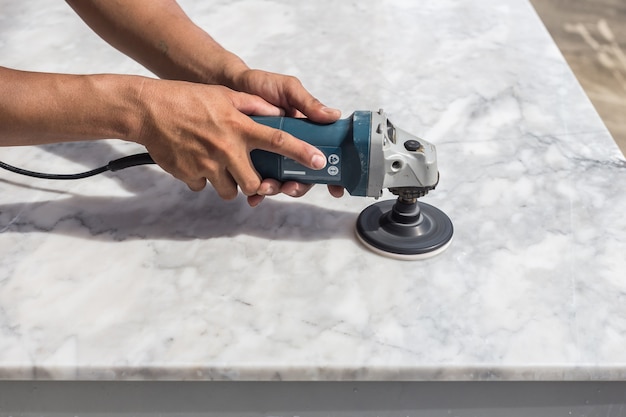 Photo man polishing marble stone table by small angle grinder