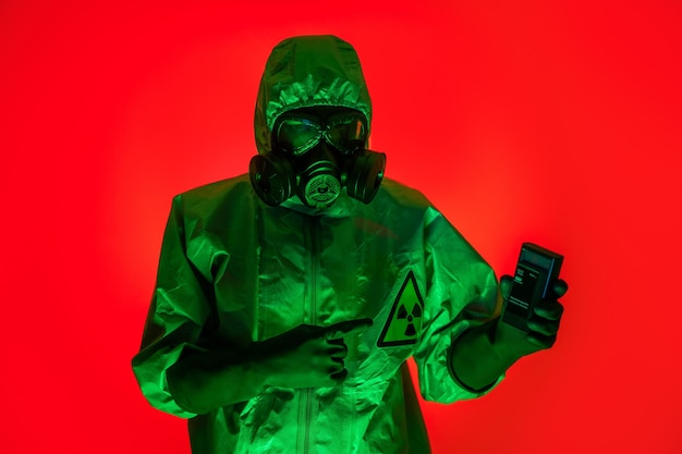 A man poses in a protective suit with a protective gas mask holding in his hand.