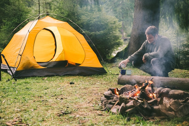 Man pour tea in metal cups tent on background