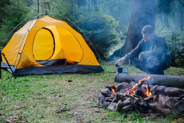 Man pour tea in metal cups tent on background