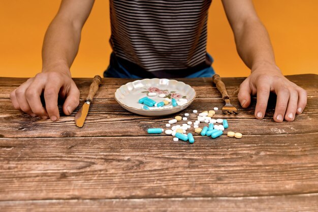 Photo the man poured various medicinal tablets into a plate and is going to eat them at the dinner table