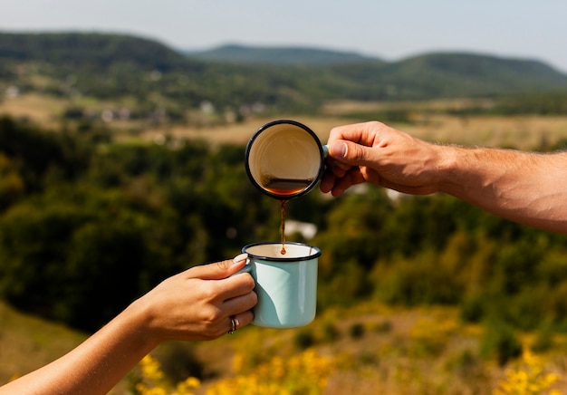 Man pouring coffee into another cup held by woman