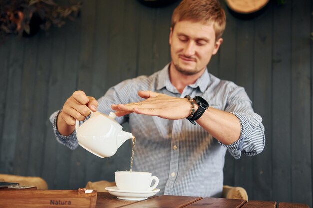 Photo a man pouring tea into a teapot with a sign saying sushi on it