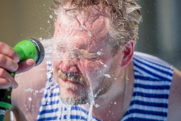 The man pours on the person water from a hose