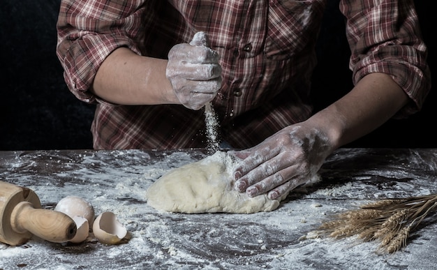 Man preparing bread dough on wooden table in a bakery close up