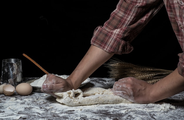 Man preparing bread dough on wooden table in a bakery close up