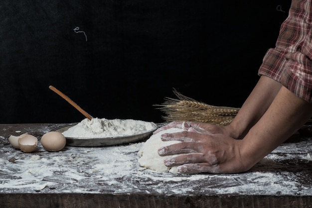 Man preparing bread dough on wooden table in a bakery close up