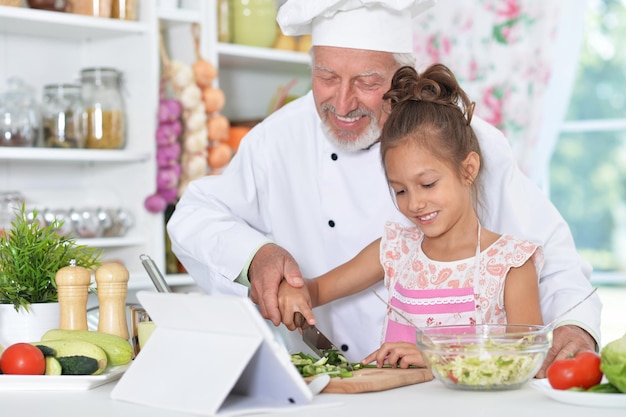 Man preparing dinner with granddaughter