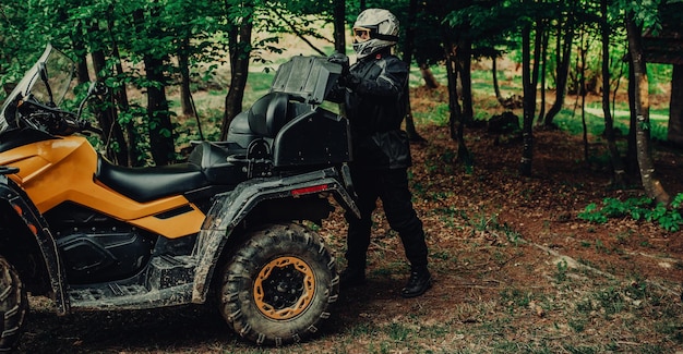 Man preparing his quad for extreme ride in forest