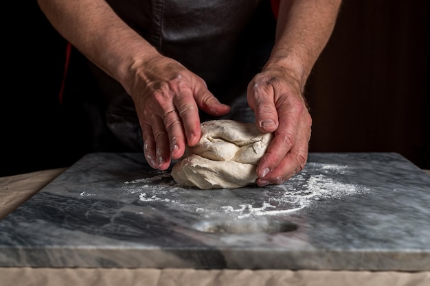 Man preparing pizza dough on marble table