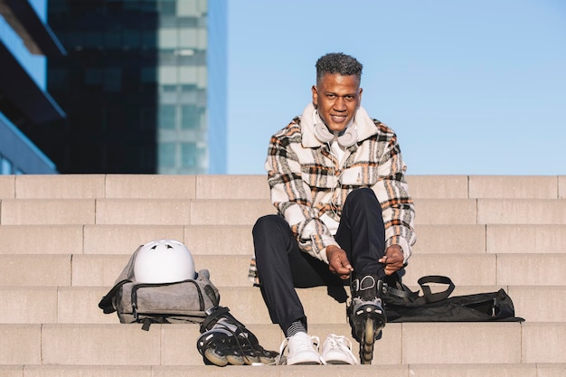 Man preparing to roller skate putting on skates Upright image