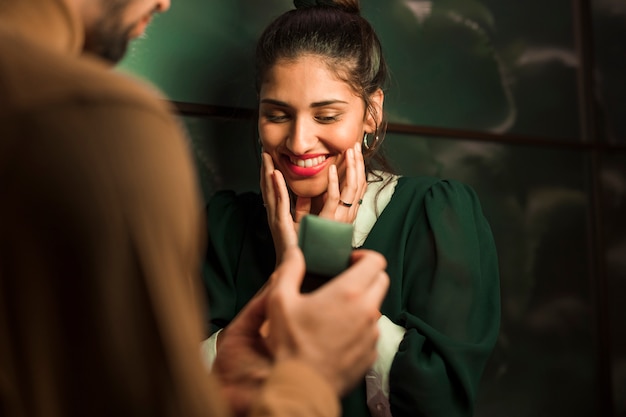 Man presenting gift in box to happy woman 