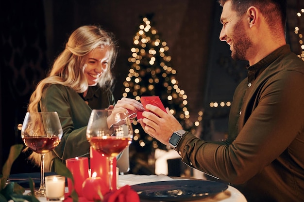 Man proposing a beautiful woman to marry him in an elegant restaurant Young lovely couple have romantic dinner indoors together