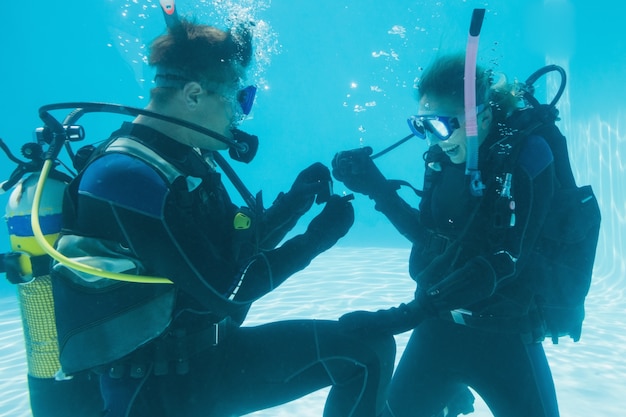 Photo man proposing marriage to his shocked girlfriend underwater in scuba gear