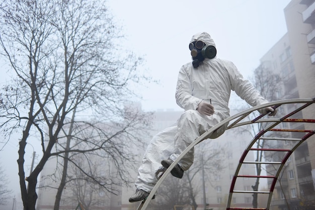 Man in protective clothing sitting on ladder on playground