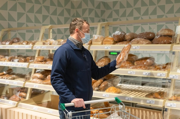 A man in a protective face mask chooses bread Quarantine Lifestyle Food and drinks