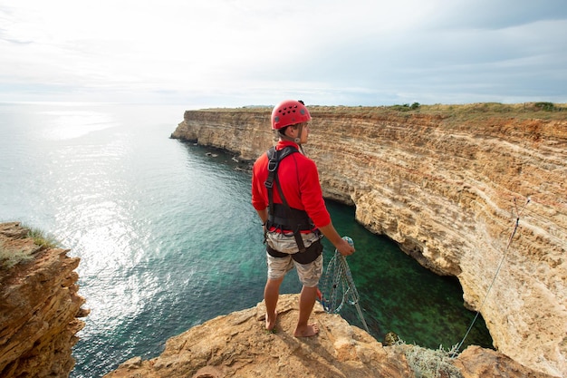 Man in protective gear and helmet on the edge of a cliff View from the back Rope jumping