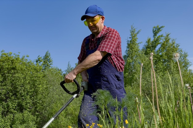 A man in protective glasses mows the grass with a lawn mower A working farmer Cutting grass