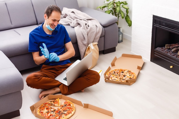 Photo man in protective gloves and mask using laptop for online food order during quarantine, closeup. delivery service