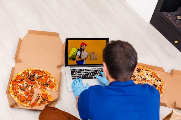 Photo man in protective gloves and mask using laptop for online food order during quarantine, closeup. delivery service