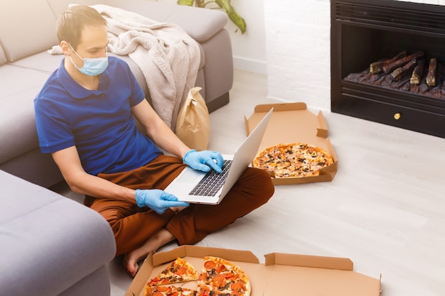 Man in protective gloves and mask using laptop for online food order during quarantine, closeup. Delivery service