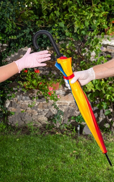 Man in protective gloves shares an umbrella with another woman in gloves