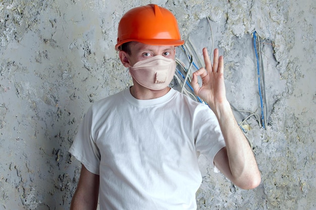 Man in protective mask and helmet on stucco wall background