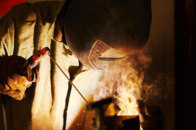 Man in protective mask welding metal construction