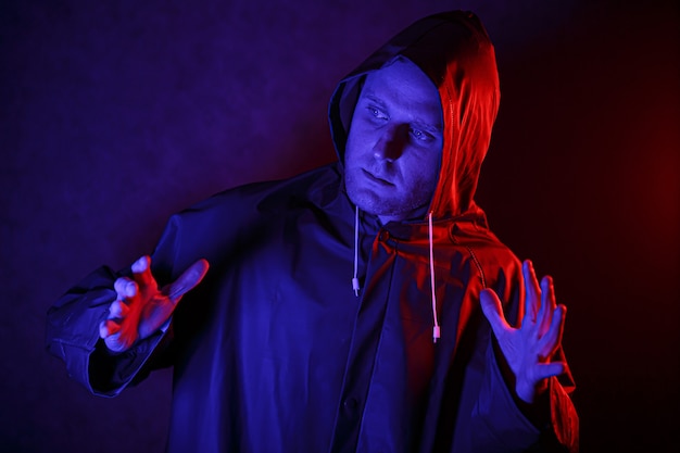 A man in a protective suit in a dark room. Halloween image concept. Virus protection. Illuminated with colored lights