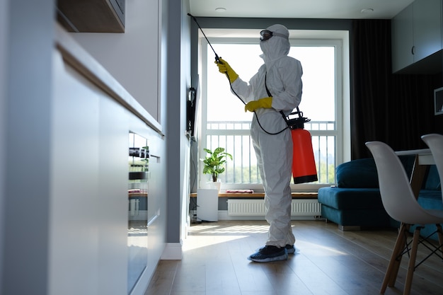 A man in a protective suit disinfects against a virus