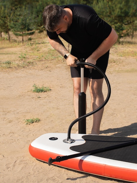 Man pumping up a sapboard on the beach