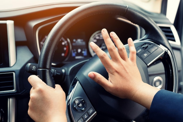 Man pushing horn while driving sitting of a steering wheel press car honking sound to warn other people in traffic concept