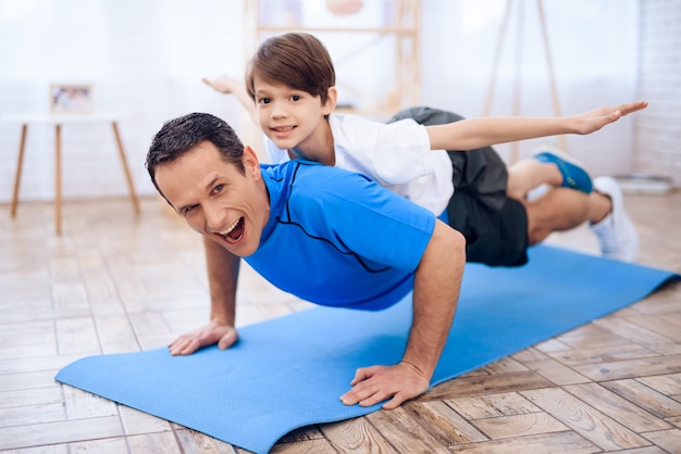 The man pushup from the floor with the boy on his back.