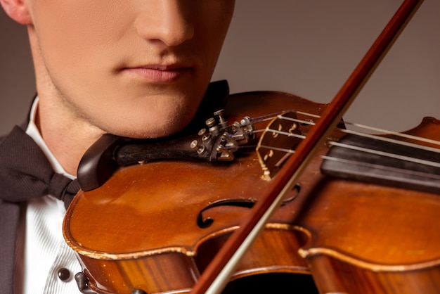 Man put the violin on his neck and plays.