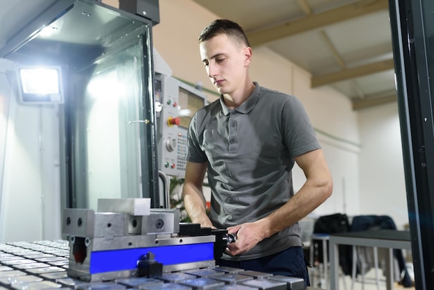 a man puts an aluminum piece on a cnc machine and prepares a processing machine
.