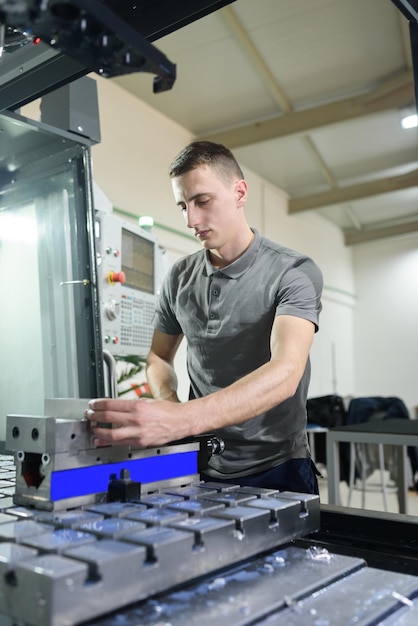 A man puts an aluminum piece on a cnc machine and prepares a processing machinexA