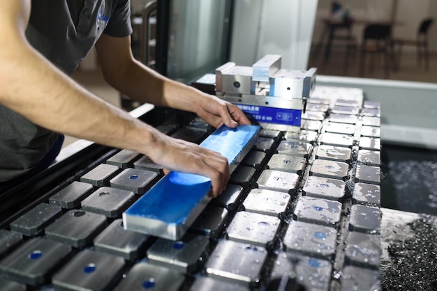 A man puts an aluminum piece on a cnc machine and prepares a processing machinexA