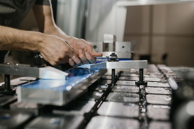 A man puts an aluminum piece on a cnc machine and prepares a processing machinexA