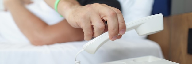 A man puts down the phone while lying in bed in a hotel closeup blurry resort service ordering