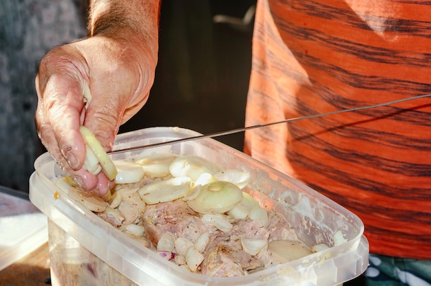 A man puts marinated meat and onions on a skewer closeup Barbecue shish kebab cooking