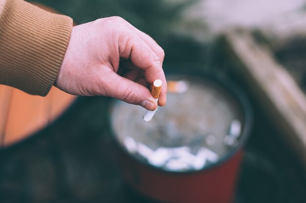 A man puts out a cigarette in the trash.