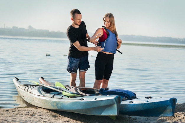 Man puts woman in life jacket to go kayaking summer vacation active sport safety