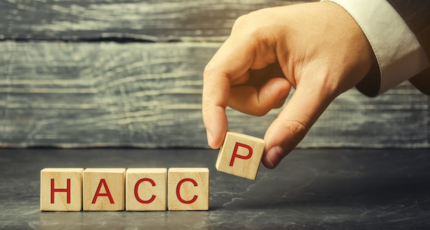 A man puts wooden blocks with the word HACCP.