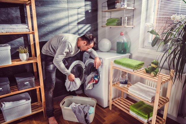 Man putting clothes into washing machine