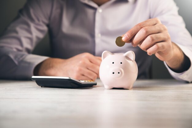 Man putting coin in piggy bank saving money finance concept