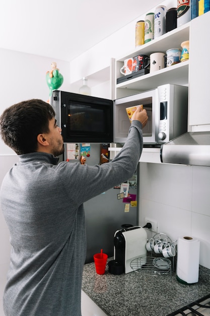 Man putting cup inside microwave oven